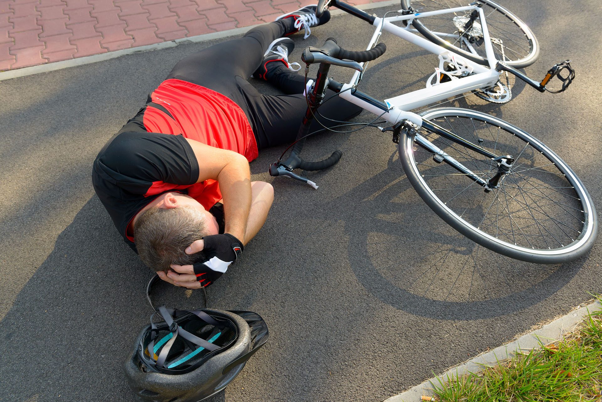 Bicycle accident. Biker lying on the road and holding his head