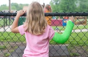 Niña con el brazo roto deseando poder jugar en el parque infantil.