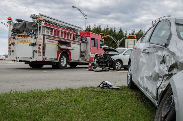 Dos coches chocan en un accidente con un camión de bomberos detrás durante un día de verano